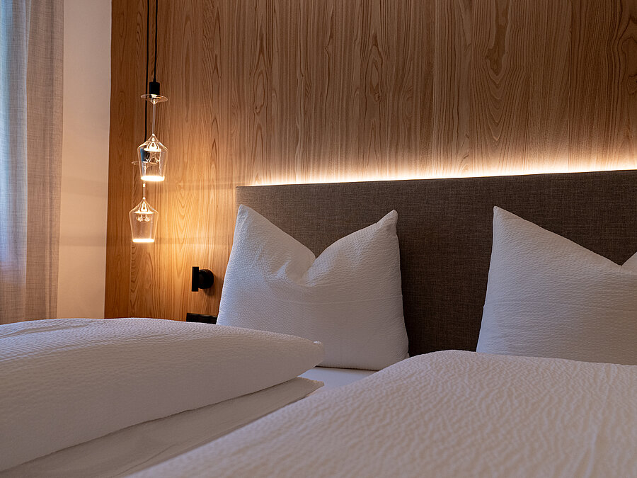 Modernes Schlafzimmer | Weingut Santer Südtirol Modernes Schlafzimmer mit hellem Holzboden, einer Holzwand, großem Einbauschrank und einem Doppelbett mit Kopfteil.