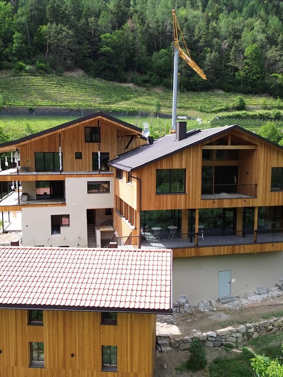 Bio-Weingut Santer mit Holzgebäuden inmitten von Weinbergen in Mühlbach, Südtirol, umgeben von grüner Natur.