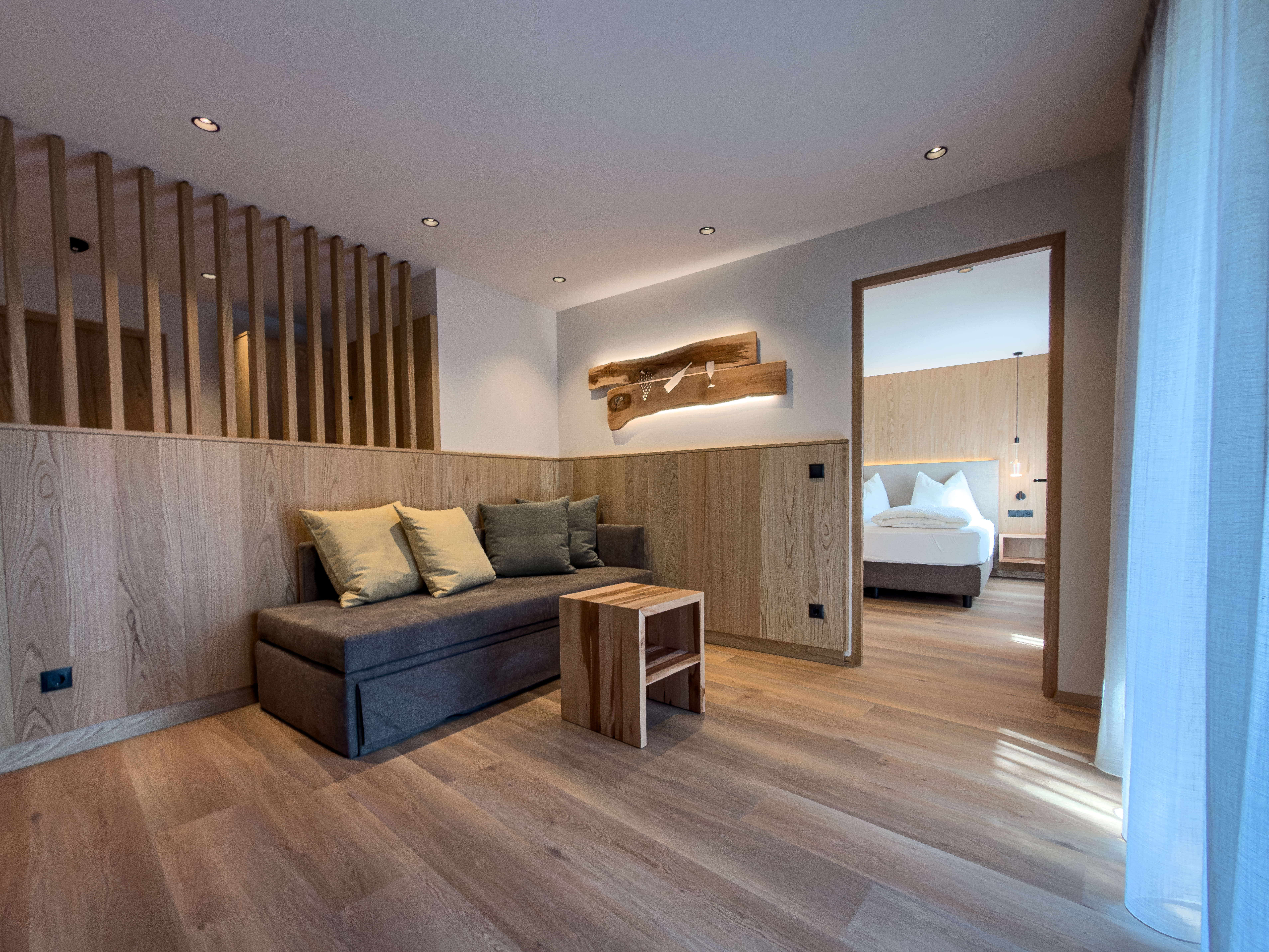 Modernes Wein-Apartment im Bio-Weingut Santer Südtirol Modernes Apartment mit stilvoller Holzeinrichtung, offener Küche, Essecke und Sofa im Bio-Weingut Santer in Südtirol.